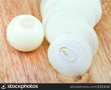 peeled onion bulb and sliced onions on wooden cutting board close up