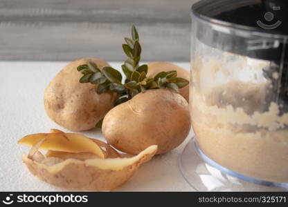 Peeled potatoes mixed in a blender on a white background. Scarlup and potatoes.