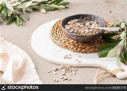 Peeled sunflower seeds in a ceramic bowl with a spoon in kitchen countertop. For healthy food and diet concepts.