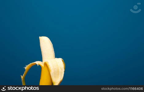 Peeled yellow banana fruit near blue background space for text, healthy concept