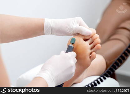 Peeling feet pedicure procedure from callus on foot by hands of podiatrist in white gloves at beauty salon. Peeling feet pedicure procedure on foot