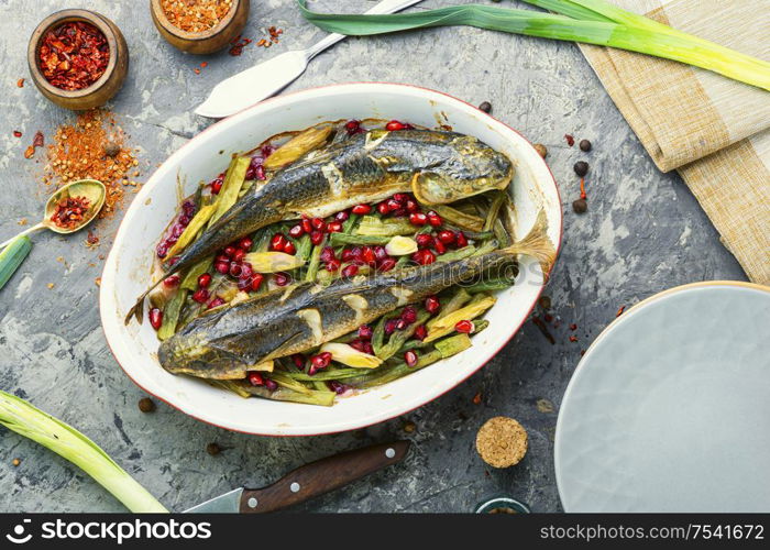 Pelengas baked with vegetables and pomegranate.Cooked roasted fish in a baking dish.. Baked fish with pomegranate