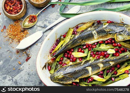 Pelengas baked with vegetables and pomegranate.Cooked roasted fish in a baking dish.. Baked fish with pomegranate