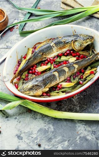 Pelengas baked with vegetables and pomegranate.Cooked roasted fish in a baking dish.. Baked fish with pomegranate