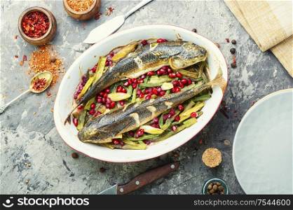 Pelengas baked with vegetables and pomegranate.Cooked roasted fish in baking dish.. Baked fish with pomegranate