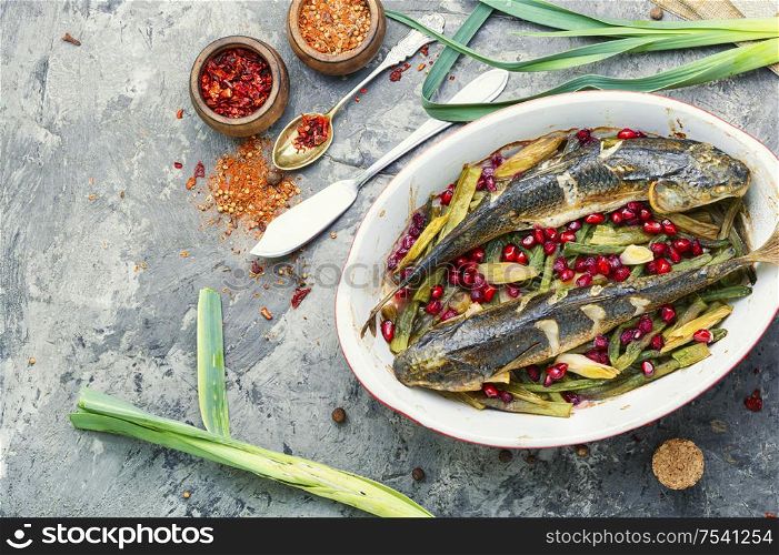 Pelengas baked with vegetables and pomegranate.Cooked roasted fish in baking dish.Space for text. Baked fish with pomegranate