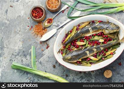 Pelengas baked with vegetables and pomegranate.Cooked roasted fish in baking dish.Space for text. Baked fish with pomegranate