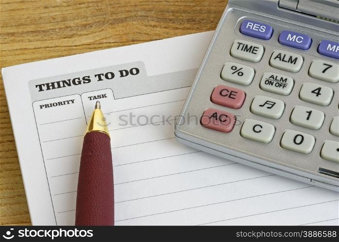 Pen and calculator on a &rsquo;Things To Do&rsquo; pad