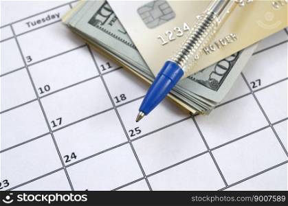 Pen and credit card on many hundred US dollar bills on calendar page close up. Business and financial planning concept. Accountant work. Pen and credit card on many hundred US dollar bills on calendar page close up