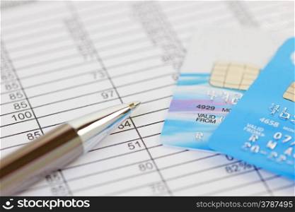 Pen and credit cards on a spreadsheet. Shallow depth of field with logos removed