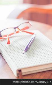 Pen and eyeglasses on notebook, stock photo