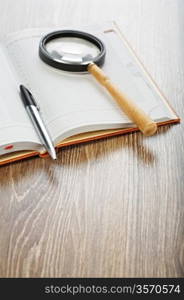 pen and magnifying glass on notebook