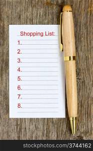 Pen and shopping list on wooden background