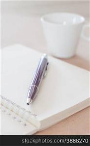 Pen and spiral notebook with coffee cup, stock photo