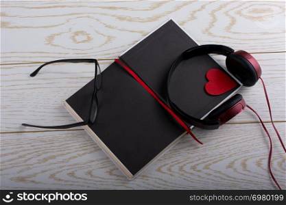 Pen, glasses, notebook and headphone on wooden texture background
