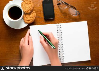 pen in female hand and an open Notepad for notes