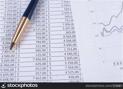 Pen lying on the financial statements. Business concept. Pen laying on printed financial reports in the form of tables with numbers
