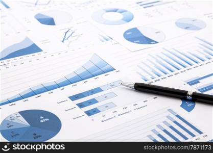 pen on blue charts, graphs, data and reports background for education and business concepts
