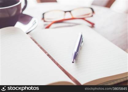 Pen on notebook with coffee cup and eyeglasses, stock photo
