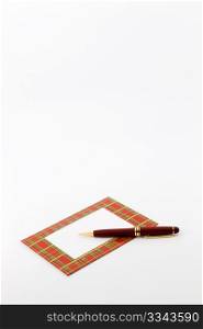 Pen sits on red plaid framed note with blank area in note and copy space above