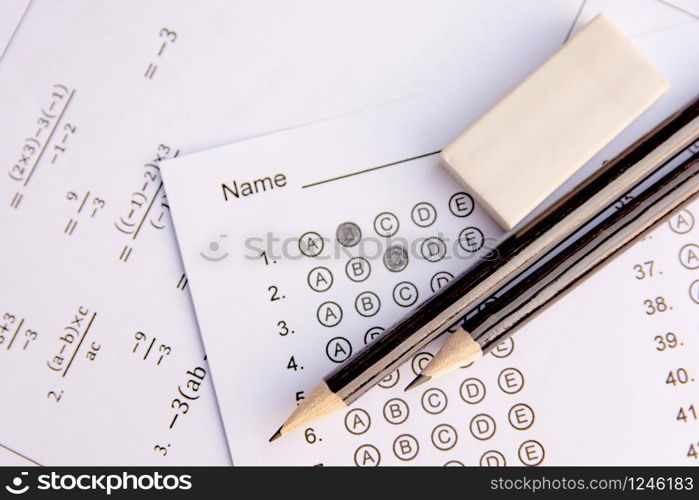 Pencil and eraser on answer sheets or Standardized test form with answers bubbled. multiple choice answer sheet