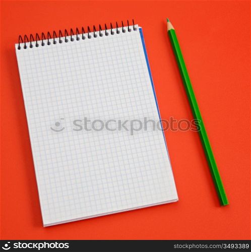 pencil and notebook over a red background