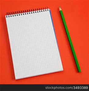 pencil and notebook over a red background