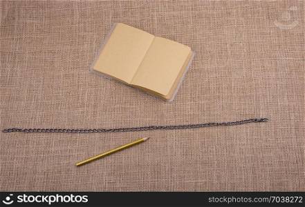 Pencil and notebook with a chain in the middle on spiral notebooks