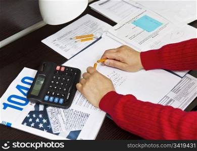 Pencil being snapped in two in front of tax forms with calculator, pencils and lamp on desktop