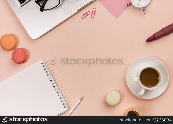 pencil macaroons spiral notepad coffee cup lipstick eyeglasses laptop peach colored backdrop