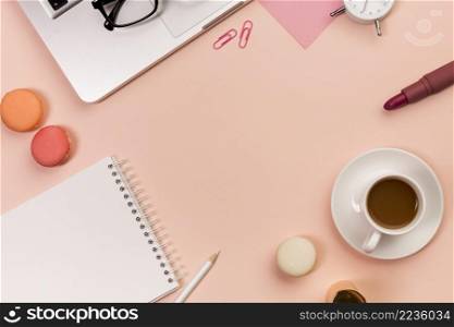 pencil macaroons spiral notepad coffee cup lipstick eyeglasses laptop peach colored backdrop