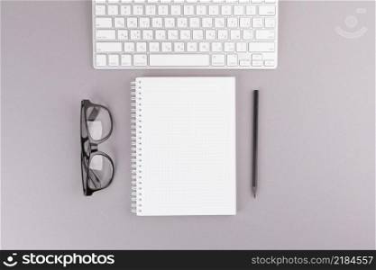 pencil near notebook keyboard eyeglasses