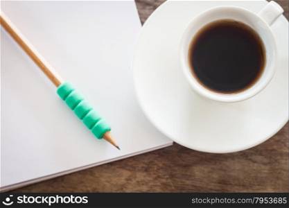 Pencil on open blank notebook with coffee cup, stock photo