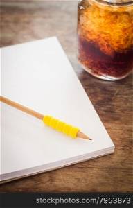 Pencil on open blank notebook with glass of iced cola, stock photo