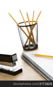 Pencils, a stapler, and spiral bound notebooks arranged on a desk.