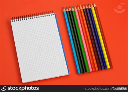 pencils and notebook over a red background