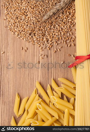 penne and wheat on wooden background