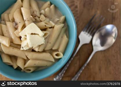 Penne carbonara with chunk of cream cheese on wood table