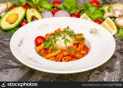 Penne pasta in tomato sauce, tomatoes decorated with parsley on a wooden background