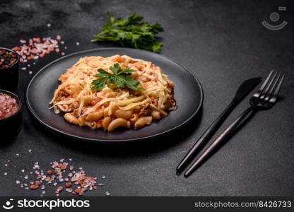 Penne pasta in tomato sauce with chicken, tomatoes decorated with parsley on a concrete background. Tasty appetizing classic italian pasta with tomato sauce and cheese on plate on dark background