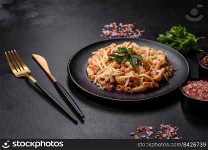 Penne pasta in tomato sauce with chicken, tomatoes decorated with parsley on a concrete background. Tasty appetizing classic italian pasta with tomato sauce and cheese on plate on dark background