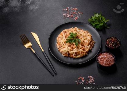 Penne pasta in tomato sauce with chicken, tomatoes decorated with parsley on a concrete background. Tasty appetizing classic italian pasta with tomato sauce and cheese on plate on dark background