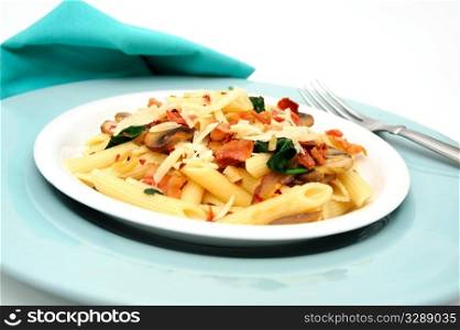 Penne Pasta Meal. Penne pasta with sauteed mushrooms garlic and Spinach with crumbled bacon and grated parmesan cheese severed on a turquoise and white plate combination.