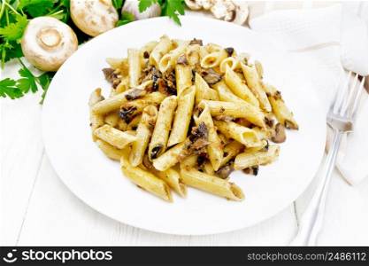 Penne pasta with wild mushrooms in a plate, napkin, parsley and fork on a wooden board background