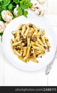 Penne pasta with wild mushrooms in a plate, towel, parsley and fork on a light wooden board background from above