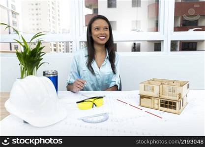 pensive african american lady chair near safety helmet model house table