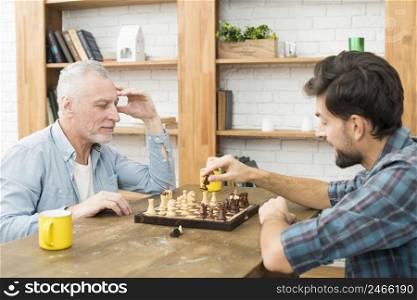 pensive aged man young guy playing chess table room
