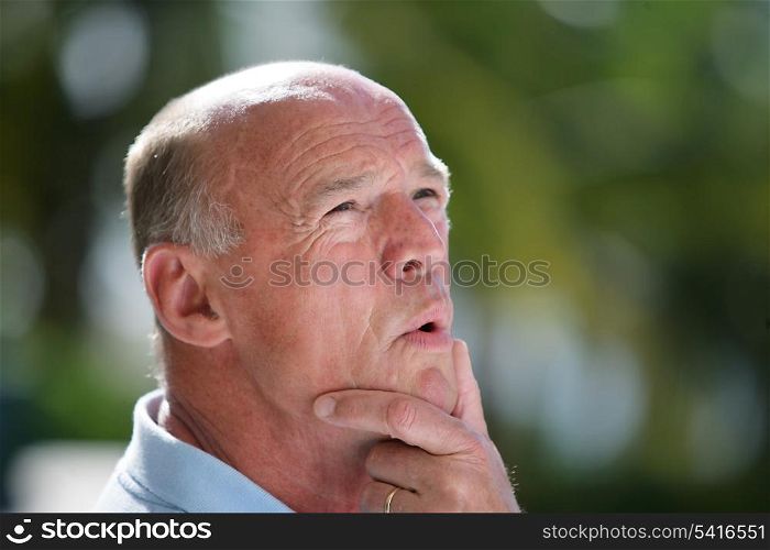 Pensive bald man stood in the garden