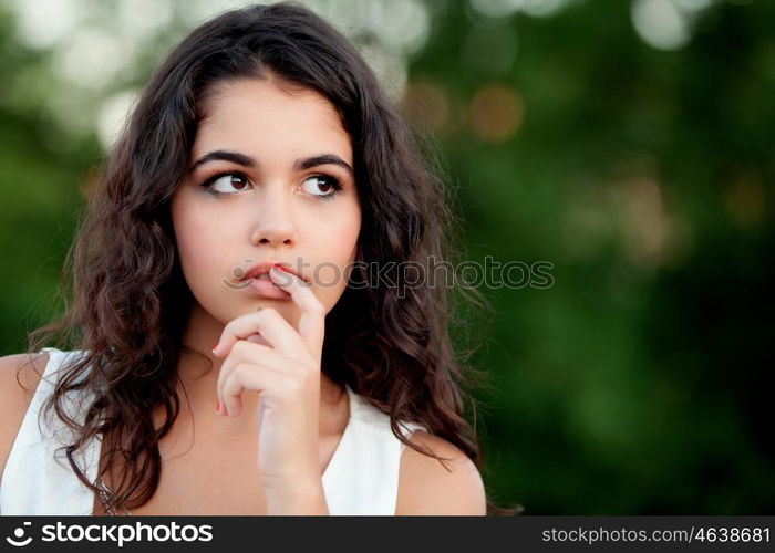 Pensive beautiful brunette girl relaxing in the park wiht many plants of background