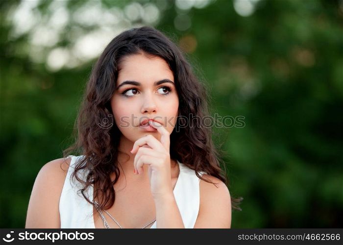 Pensive beautiful brunette girl relaxing in the park wiht many plants of background